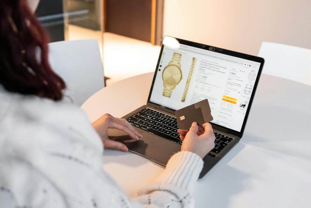 A woman making an online purchase using a laptop and credit card at home.